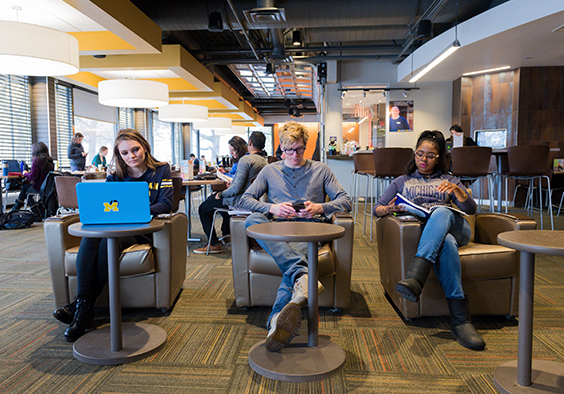 Photo of three students reading and studying inside.