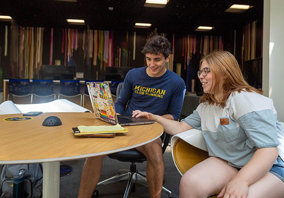Photo of two students looking at a computer.