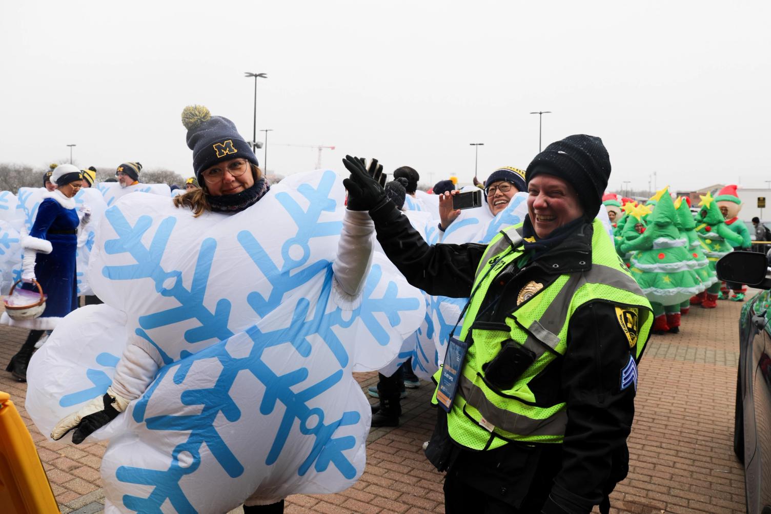 A U-M police officer high-fives a football game attendee dressed as a snowflake.