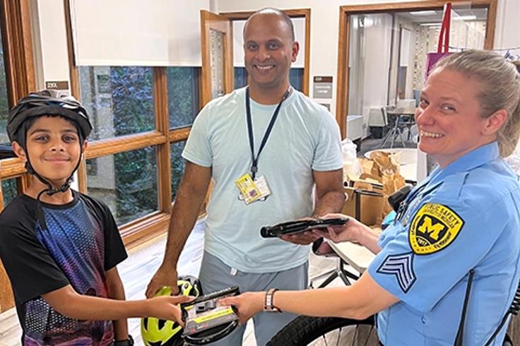 A friendly officer presents a bicycle lock to a delighted boy, showcasing a positive interaction between them.