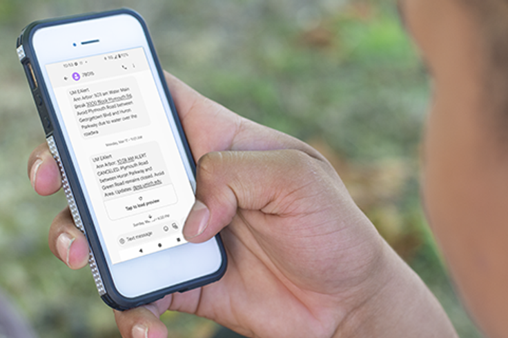 Photo of a person looking at a U-M Emergency alert on their phone.