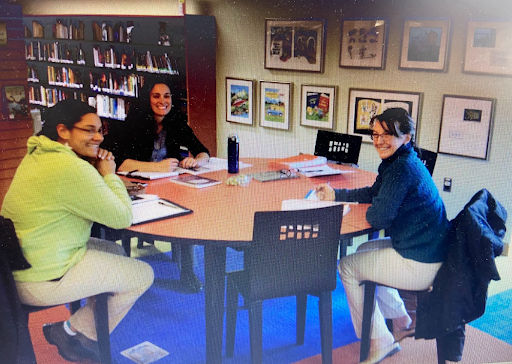 Three members of the SVU team sit around a table, smiling.