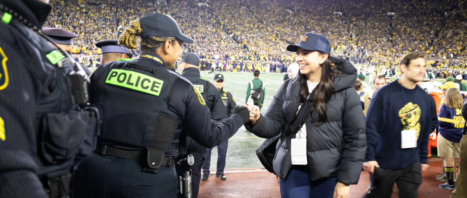 Photo of a UMPD officer fist-bumping with a football fan.