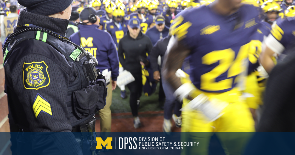 A police officer watches football players as they run by.
